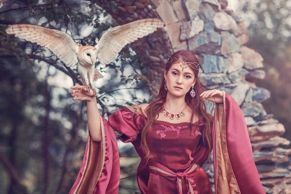 Güzel ortaçağ kadın, büyücü, elini üzerinde uçan bir kuşu ile. İnanılmaz sahne yakınındaki antik ark.