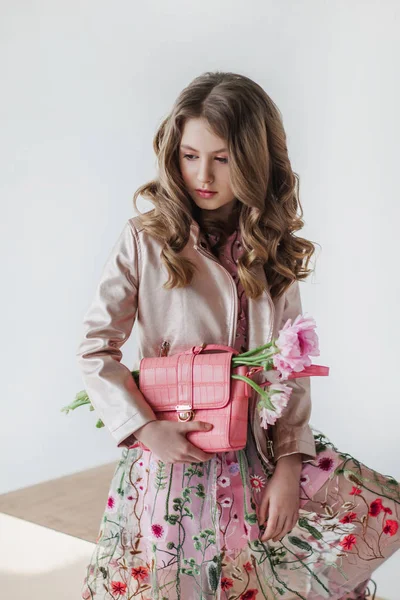 Mercan çanta ve pembe çiçekler ile güzel genç moda kız