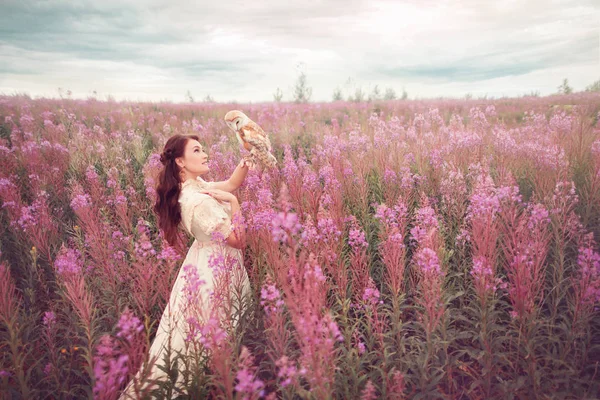 Baykuşlu ortaçağ kadını pembe çiçek tarlasında kalıyor..