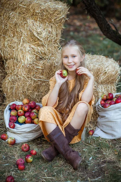 Mavi gözlü, uzun sarı saçlı, geçmişe dönük sarı elbiseli gülümseyen küçük bir kızın portresi. Dışarısı sakin ve kırsal.
