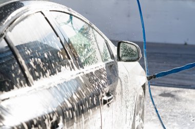 Arabayı yıkamak, otomobili araba şampuanıyla kaplamak, siyah araba yıkama, seçici odaklanma.