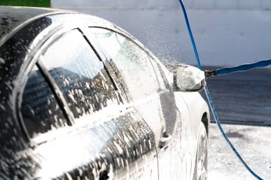 Arabayı yıkama, çatıyı araba şampuanıyla kaplama, siyah araba yıkama, seçici odaklanma.