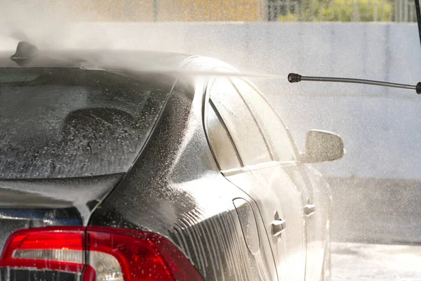 self-washing the car, washes away car shampoo from roof, black car washing, selective focus