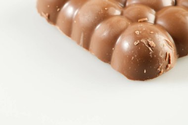 Beyaz arka planda lezzetli gözenekli çikolata. Tatlı ve lezzetli sütlü çikolata yakın plan, seçici odaklanma