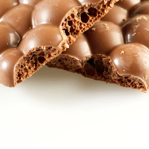 Tasty porous chocolate bar on white background. Sweet and tasty milk chocolate closeup, square photo, selective focus