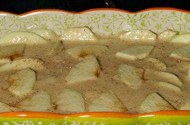 yeşil elma parçaları sıvı hamur etrafında az kabarcık, elmalı tatlı pasta elektrikli fırında pişiyor.