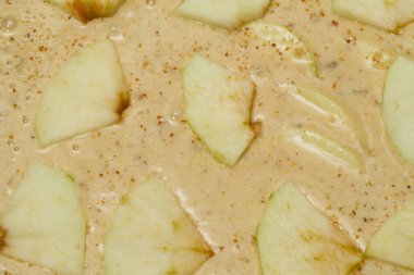 yeşil elma parçaları sıvı hamur etrafında az kabarcık, elmalı tatlı pasta elektrikli fırında pişiyor.