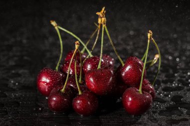 Kiraz su siyah bir zemin üzerine bırakır. Olgun kiraz. yaz meyveleri kavramı kopya alanı ile