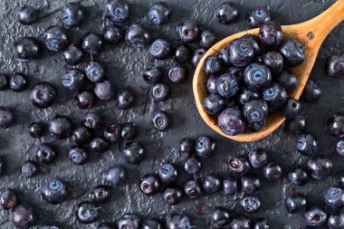 Bir tahta kaşık karanlık taş tablo içinde taze yaban mersini. Diyet ve sağlıklı beslenme kavramı. Olgun ve sulu taze çilek aldı. Üstten görünüm