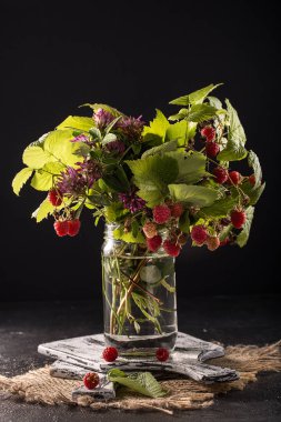 Orman meyveleri yapraklarda rustik arka plan ile. ahududu cam kavanozda dalı. Yaz hasat çilek