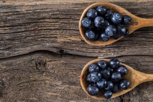 blueberry with wooden spoon on wooden table. Freshly picked blueberries in the range of wooden spoons. Juicy and fresh blueberries on rustic table. Blueberry on wooden background. Concept of healthy eating and nutrition for all family