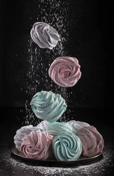 Colored Marshmallow or Zephyr   flying in freeze motion,  in powdered sugar. Concept of flying food. Homemade sweets
