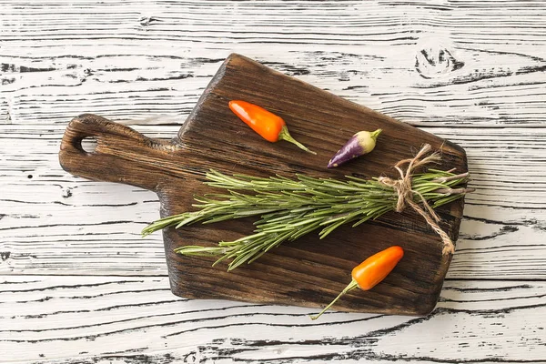 Cutting Board, rosemary and spices. background rosemary, chili pepper on a wooden table.  Herb and spice ingredients on  wooden white background