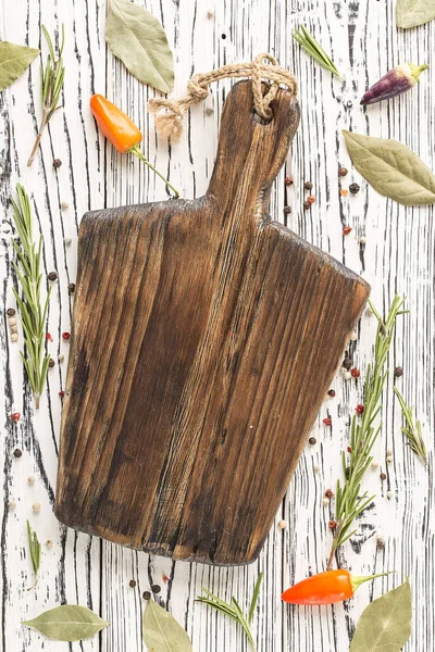 Cutting Board, rosemary and spices. background rosemary, chili pepper on a wooden table.  Herb and spice ingredients on  wooden white background