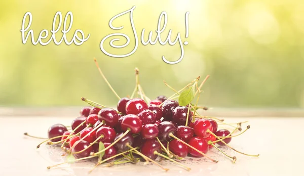 HELLO JULY greeting card. cherries on wooden table. — Stock Photo, Image