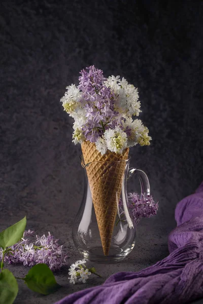 Cône de gaufre avec lilas violet et blanc sur fond gris foncé — Photo