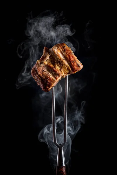 Garfo com pedaços de carne grelhada deliciosa no fundo preto. — Fotografia de Stock