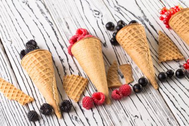 Ahşap arka planda waffle koni yaz meyveleri