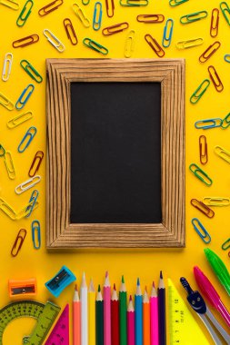 Sarı kağıt arka plan üzerinde Renkli Okul kırtasiye ve tebeşir tahtası.