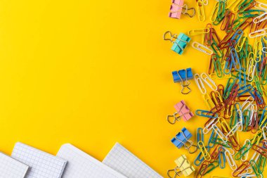 Sarı arka planda renkli ataşlar ve bağlayıcı klipler, kopyalama alanı