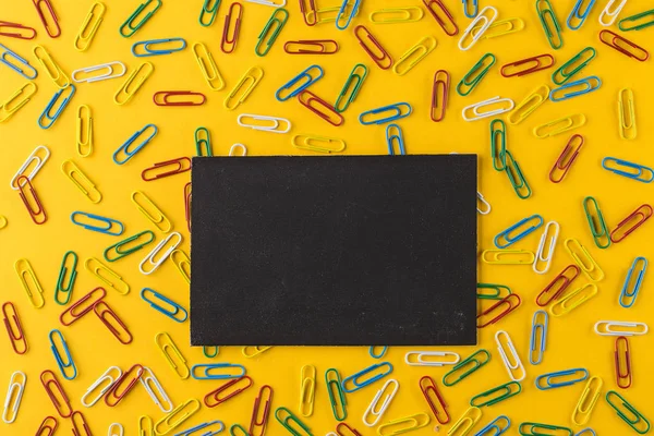 Скрепки и пустая рамка на фоне желтой бумаги . — стоковое фото