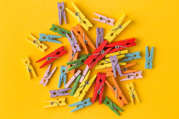 Pequenos pinos de roupas coloridas no fundo amarelo . — Fotografia de Stock