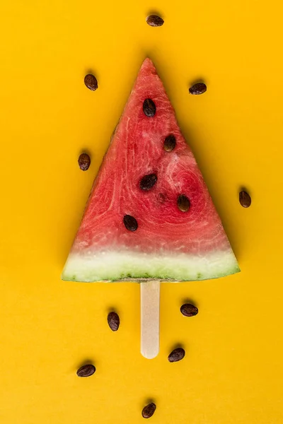Watermelon slice on bright yellow paper background.