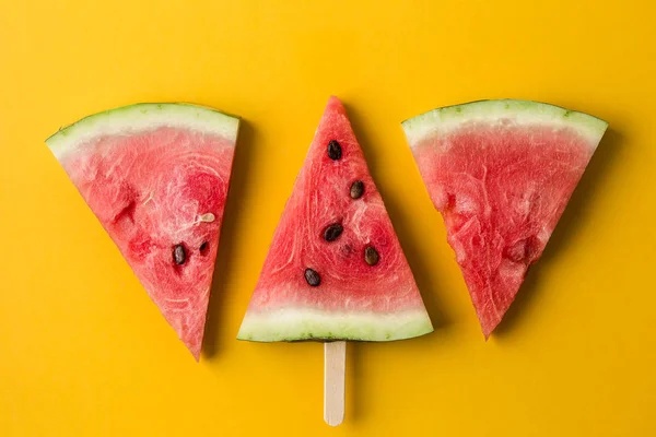 Three slices of watermelon on bright yellow paper background. — Stock Photo, Image