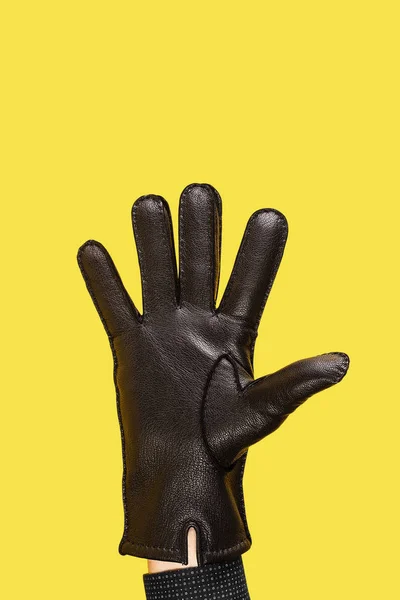 Mano en guantes de cuero negro sobre fondo amarillo —  Fotos de Stock