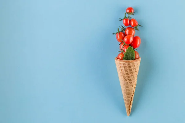 Tomates frescos saludables en conos de gofre sobre fondo azul —  Fotos de Stock