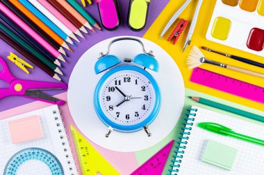 Yaratıcı düz görünüm, okul konseptine ve alarmlı saate dayanıyor. Sabit, okula dönüş, yaz tatili, eğitim konsepti. Kağıt arkaplanda okul malzemeleri. metin veya tasarım için şablon