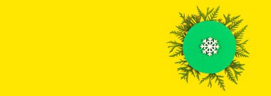 Noel afişi, kozalaklı ağaç dalları ve sarı kağıtta kar taneleri. Noel ağacı dallarının yuvarlak çerçevesi ve metin için yeri olan dekorasyonlar. Üst Manzara. Yeni yıl kavramı