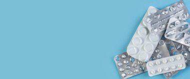 Mavi arka planda kullanılmış bir yığın hap. Tıbbî kabarcıklar haplar olmadan açıldı ve boşaldı. Metin için alanı olan tıbbi geniş afiş.