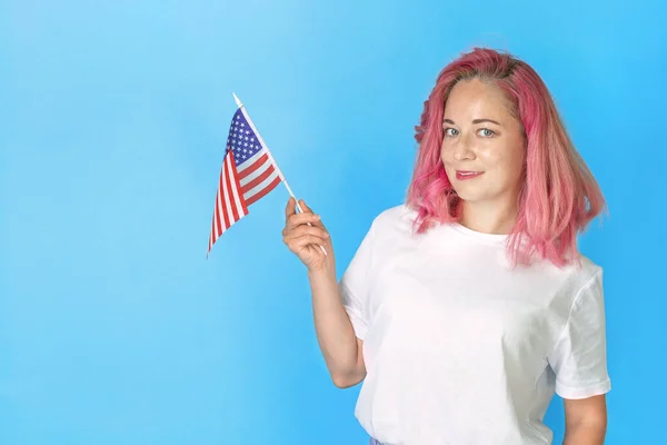 Young girl student holds american small flag and smiles on blue background