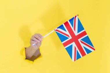 Sarı yırtık kağıttan İngiliz bayrağı tutuyordu. Birleşik Krallık bayrağı