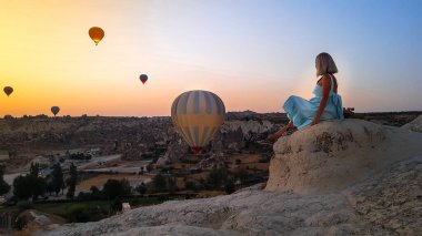 Kapadokya, Türkiye 'de vadide uçuşan renkli sıcak hava balonları gibi seyreden bir kadın. Romantik sahne Kapadokya, Türkiye