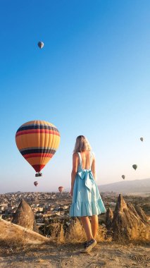 Kapadokya, Türkiye 'de vadide uçuşan renkli sıcak hava balonları gibi seyreden bir kadın. Romantik sahne Kapadokya, Türkiye