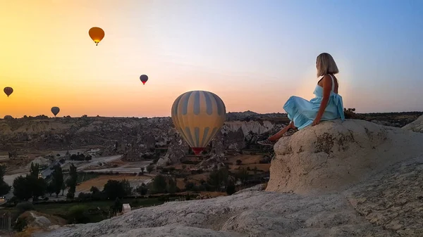 Kapadokya, Türkiye 'de vadide uçuşan renkli sıcak hava balonları gibi seyreden bir kadın. Romantik sahne Kapadokya, Türkiye