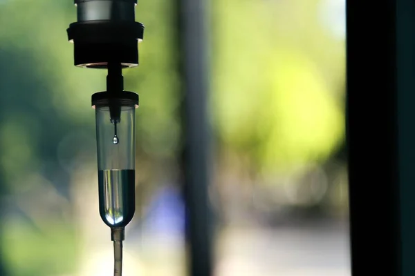 Damardan damar içi sıvı damlası salin damlası hastane odası, tıbbi konsept, tedavi acil durumu ve enjeksiyon ilacı infüzyon tedavisi kemoterapisi, konsept ayarlayın. Mavi ışık arka plan, seçici odaklanma 