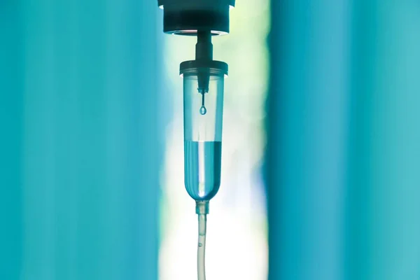 Damardan damar içi sıvı damlası salin damlası hastane odası, tıbbi konsept, tedavi acil durumu ve enjeksiyon ilacı infüzyon tedavisi kemoterapisi, konsept ayarlayın. Mavi ışık arka plan, seçici odaklanma 