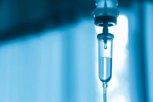 Damardan damar içi sıvı damlası salin damlası hastane odası, tıbbi konsept, tedavi acil durumu ve enjeksiyon ilacı infüzyon tedavisi kemoterapisi, konsept ayarlayın. Mavi ışık arka plan, seçici odaklanma 