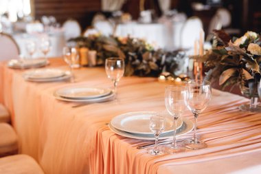 Boş şarap kadehleriyle presidyum masa ayarları. Restorandaki beyaz masada beyaz ve kırmızı şarap için tabaklar ve şarap kadehleriyle selebration ziyafetini kapat.