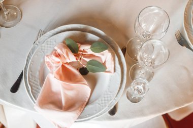 Boş şarap kadehleri ve tabağı olan en iyi manzara masa ayarı. Beyaz tabaklar, pembe peçete ve şarap kadehleri ile kutlama ziyafeti. Restorandaki beyaz ve kırmızı masada.