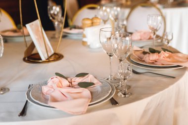 Boş şarap kadehleriyle şenlik masası ayarları. Restorandaki beyaz ve kırmızı masada pembe peçeteler, beyaz tabaklar ve şarap kadehleriyle kutlama ziyafeti