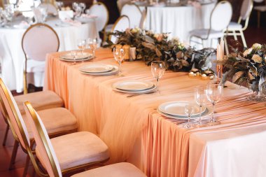 Boş şarap kadehleriyle presidyum masa ayarları. Lokantadaki beyaz masada beyaz ve kırmızı şarap için tabaklar ve şarap kadehleriyle kutlama ziyafeti