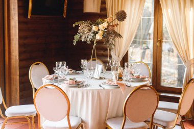 Boş şarap kadehleriyle şenlik masası ayarları. Restorandaki beyaz ve kırmızı masada pembe peçeteler, beyaz tabaklar ve şarap kadehleriyle kutlama ziyafeti