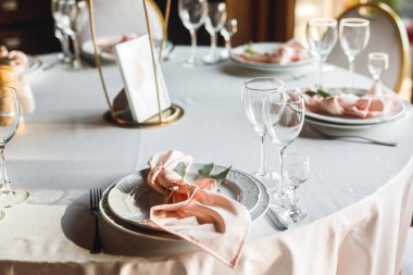 Kutlama masasını boş şarap kadehleri ve numaralı masalarla kapat. Beyaz tabaklar, pembe peçete ve şarap kadehleri ile kutlama ziyafeti. Restorandaki beyaz ve kırmızı masada.