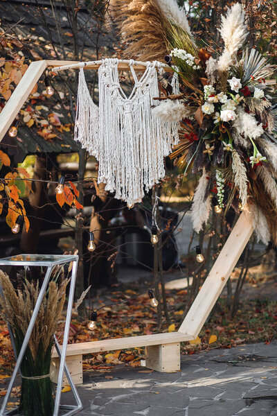 Wedding ceremony with arch in rustic style with macrame. Wedding exit ceremony with wood arch with fresh flowers and pampass grass