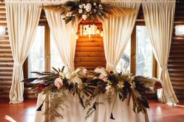 Düğündeki yeni evlilerin yakın plan başkanlığı. Restoranda taze çiçekli gelin ve damat için bir masa. Yeni evliler için ziyafet masası. Lüks düğün ziyafeti dekorasyonu