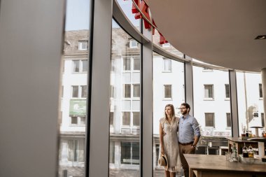 Restorantın panoramik pencerelerinin yanında romantik bir çift. Mutlu aile kucaklaşır Pencereden bakar